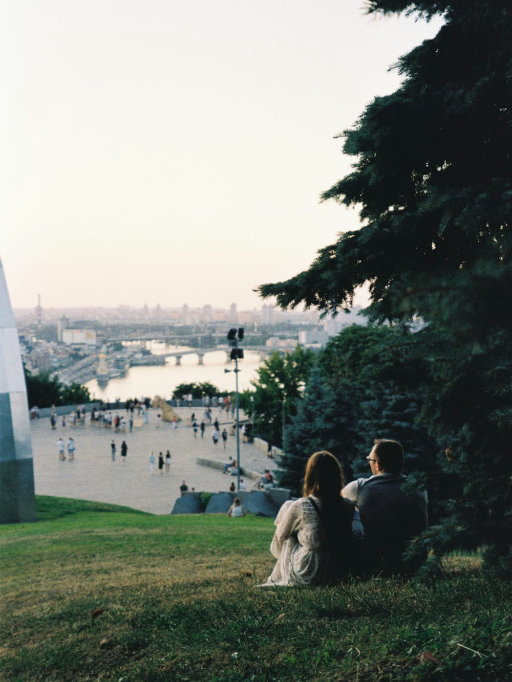 people sitting on green grass field near body of water during daytime