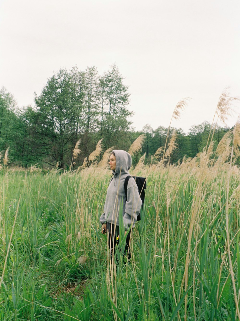 woman in gray coat walking on green grass field during daytime