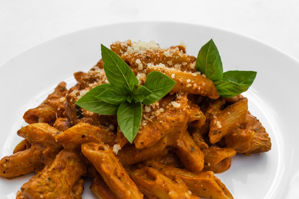 brown pasta with green leaves on white ceramic plate