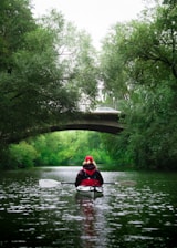 man in red jacket riding on boat on river during daytime