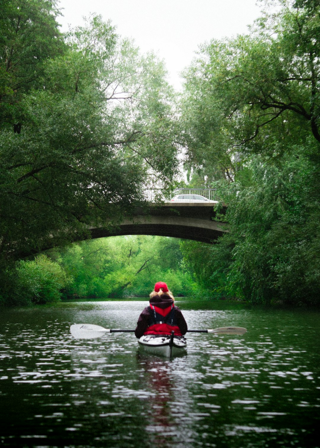 man in red jacket riding on boat on river during daytime