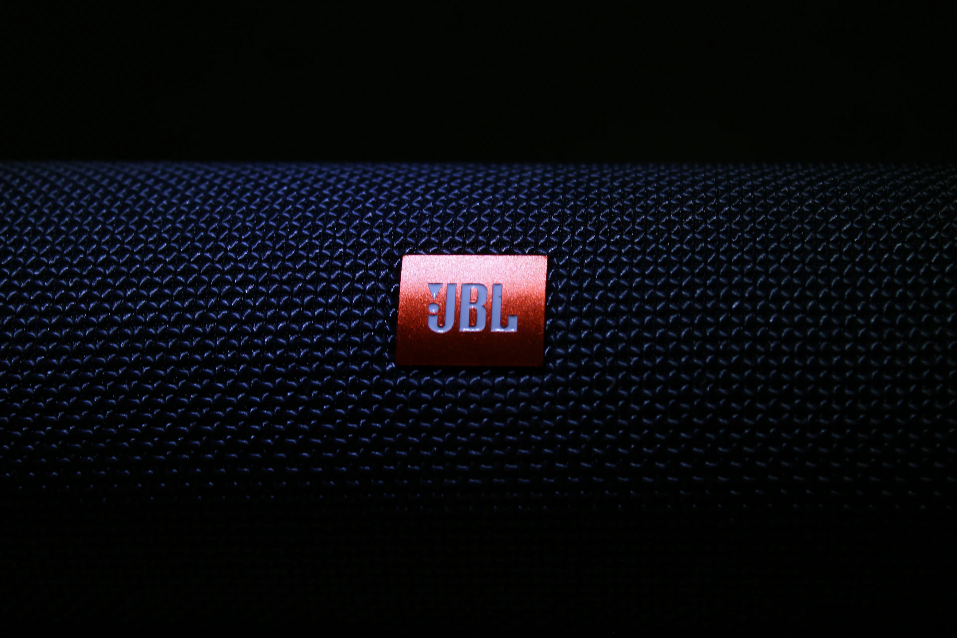 black jbl portable speaker on black textile