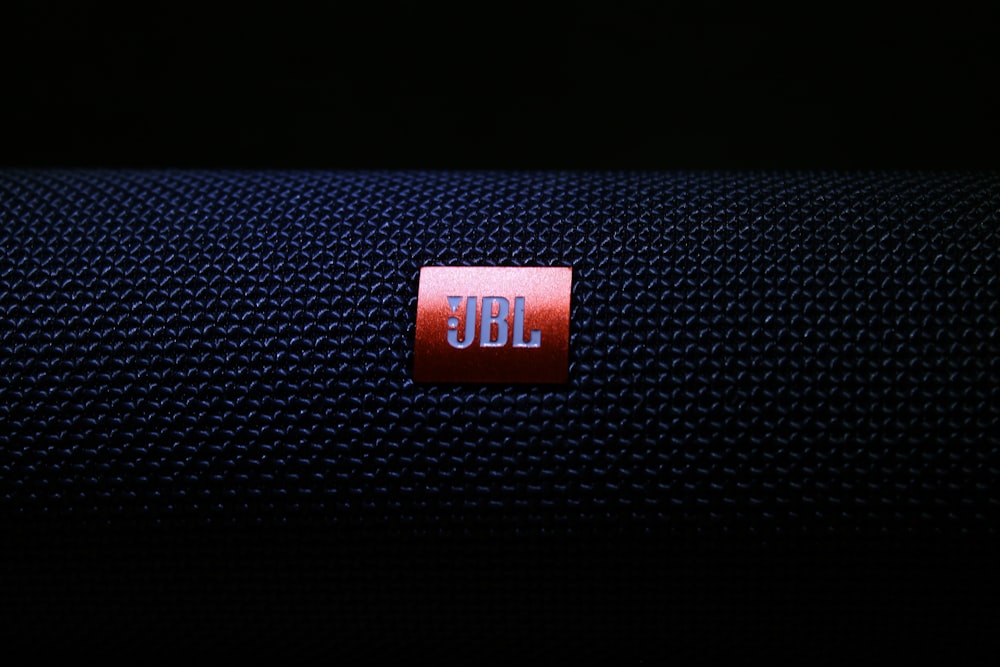 black jbl portable speaker on black textile