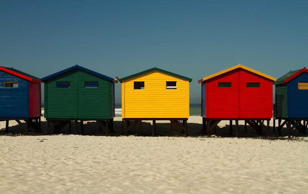 red and blue wooden houses on white sand during daytime