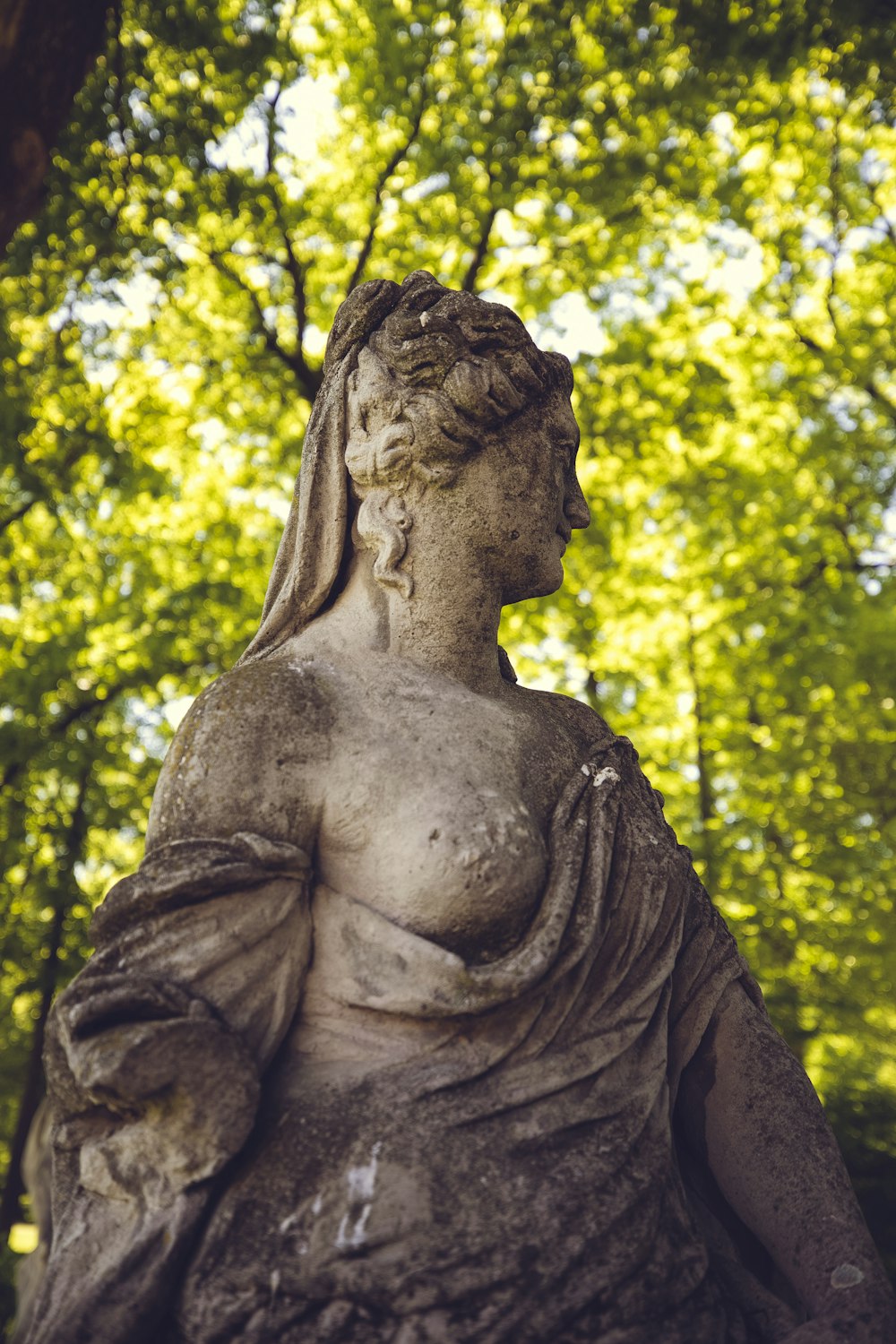 statue de femme près d’arbres verts pendant la journée