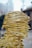 A sculpture composed of yellow metal wires intricately woven to form a human head. The wires create a hollow structure with a mesh-like appearance, set against an urban backdrop with buildings and blurry skies. The design exhibits a blend of abstract art and human form.