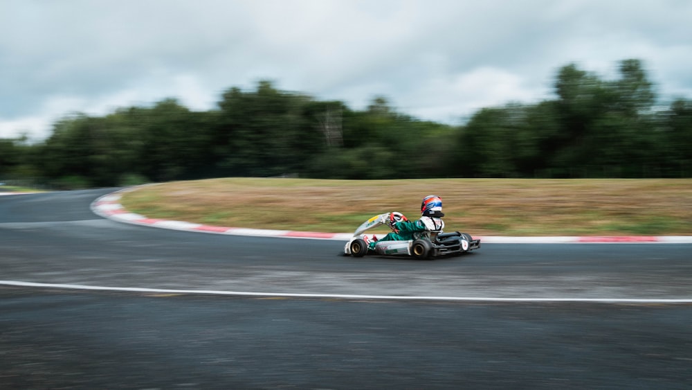 昼間の道路で緑と黒のスポーツカーに乗る男