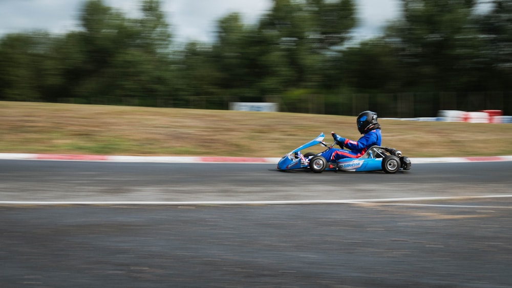 man riding blue and black go kart on track during daytime