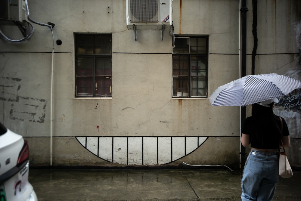 person in blue denim jeans holding white umbrella