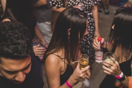 People gathering, having fun, and holding cocktail drinks at Hinges Bar in Houston, Texas.