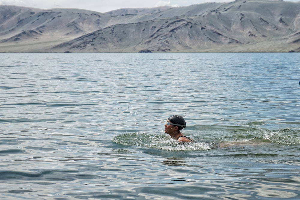 man in blue and white shorts swimming on sea during daytime