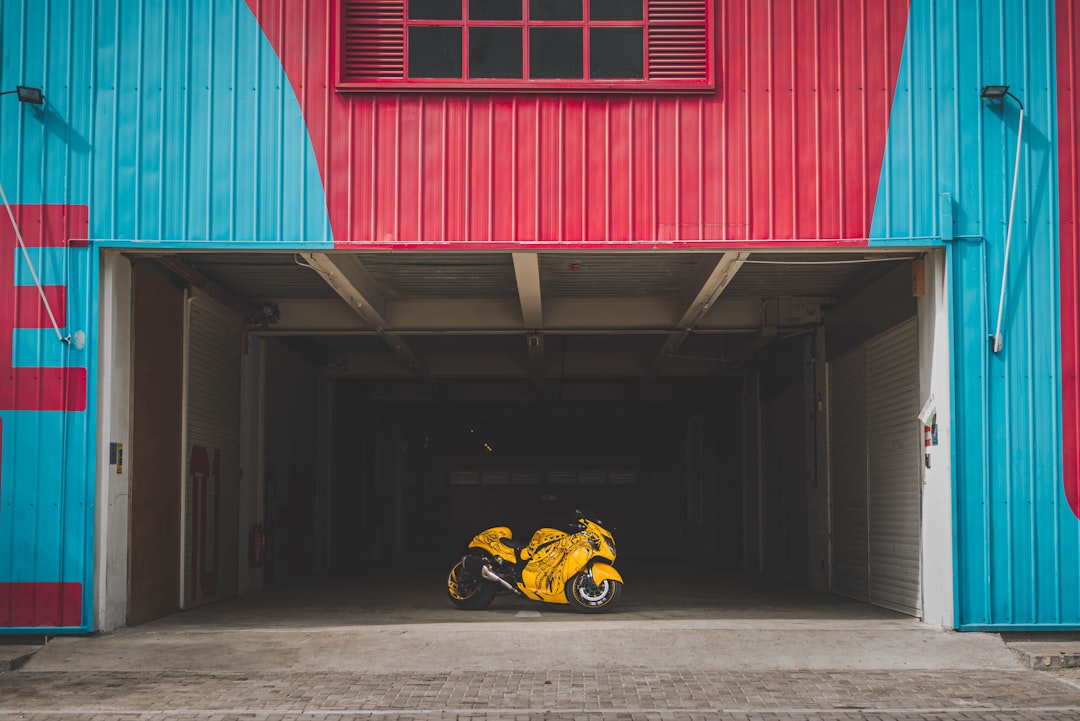 yellow sports bike parked beside blue and pink building