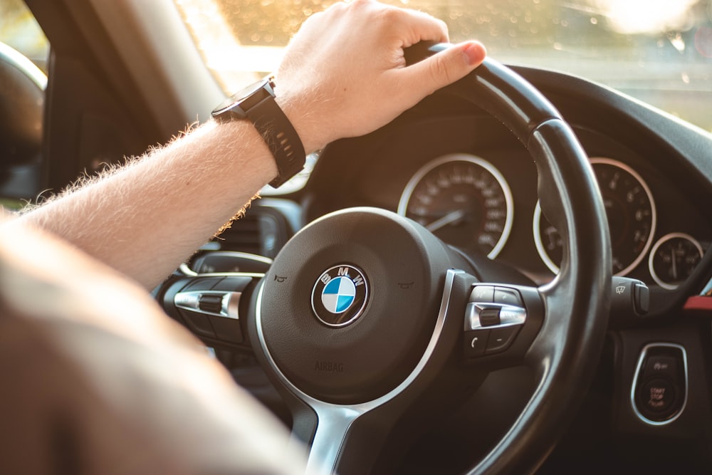 person holding black bmw steering wheel