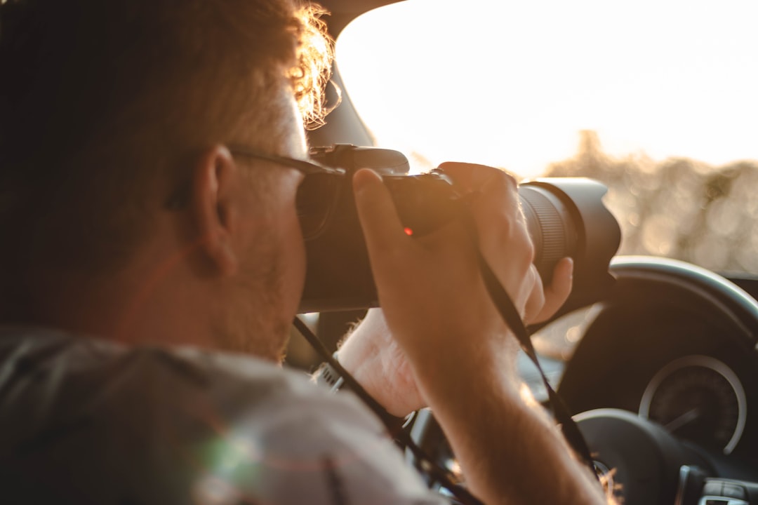 man in white shirt drinking from black binoculars