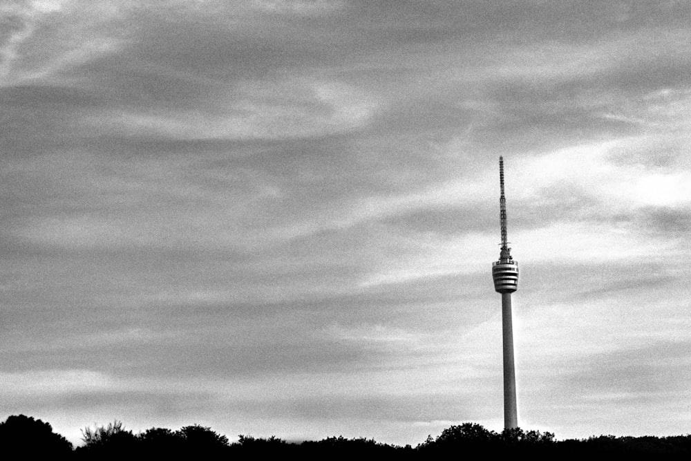 grayscale photo of tower under cloudy sky