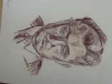 A sketch of a man drawn with rough, dark lines. The image focuses on detailed facial features, including deep-set eyes and a stern expression. The drawing style is reminiscent of classic charcoal or pencil sketches, with a textured and slightly chaotic appearance.