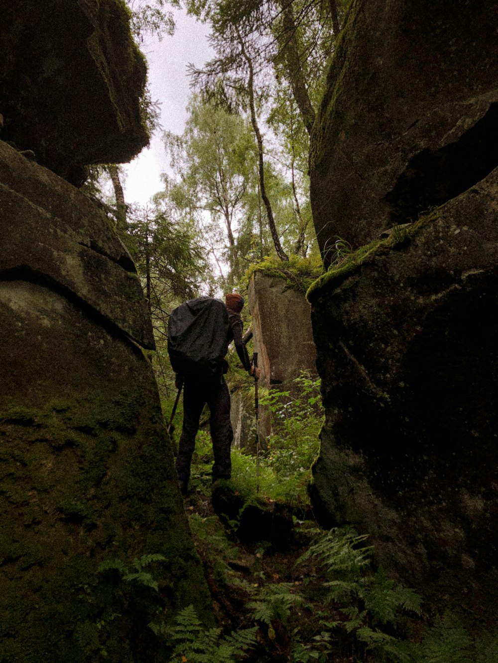 man in black jacket and black pants standing on brown rock formation during daytime