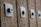 A close-up view of a series of metal bolts or studs affixed to a wooden surface, creating a textured pattern. Each bolt is embedded in a square metal plate, and the image captures a sense of rustic or industrial design.