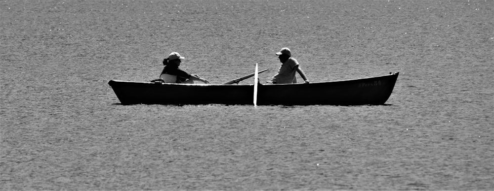2 men riding on boat in grayscale photography