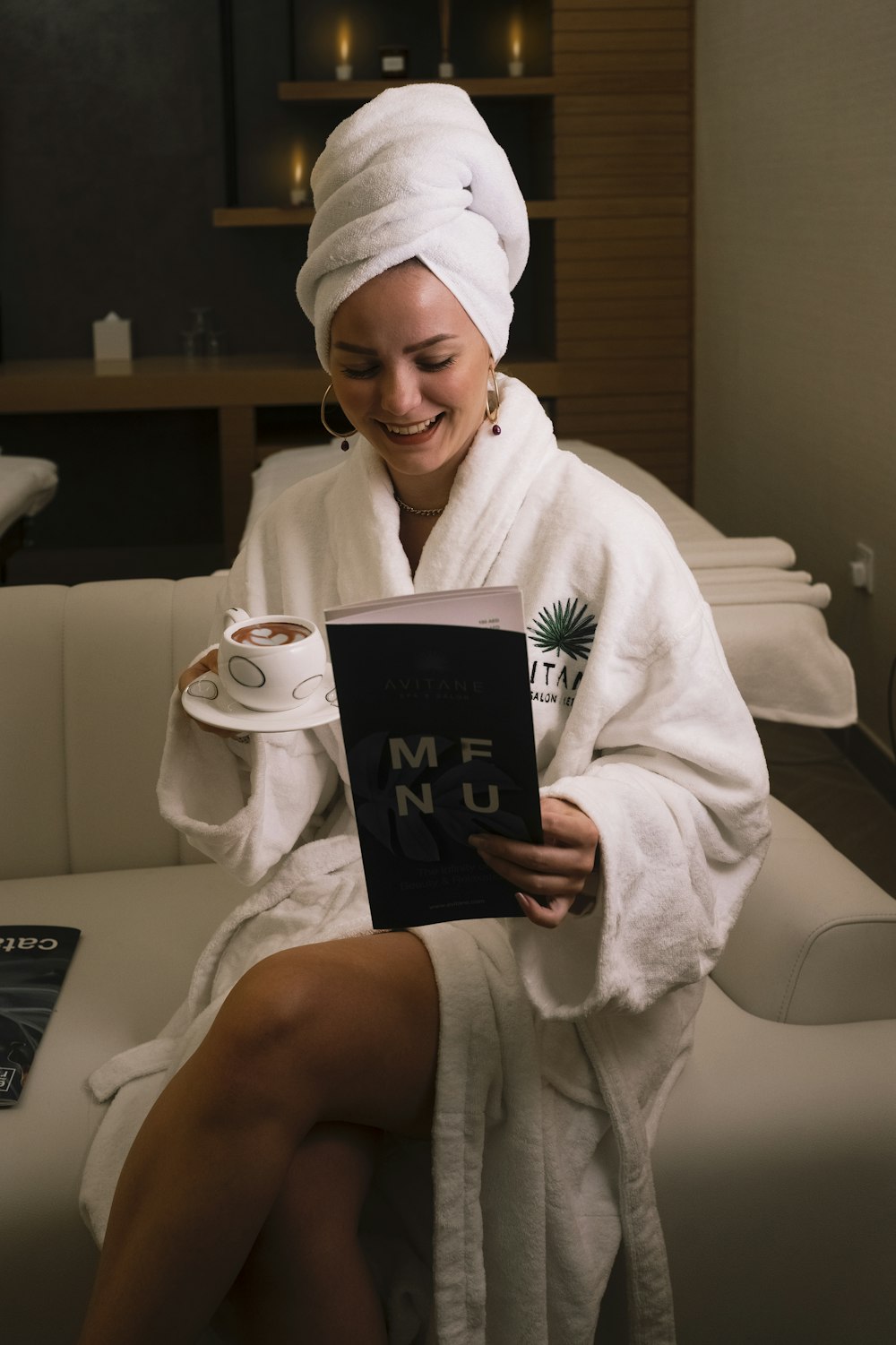 woman in white bathrobe holding black book