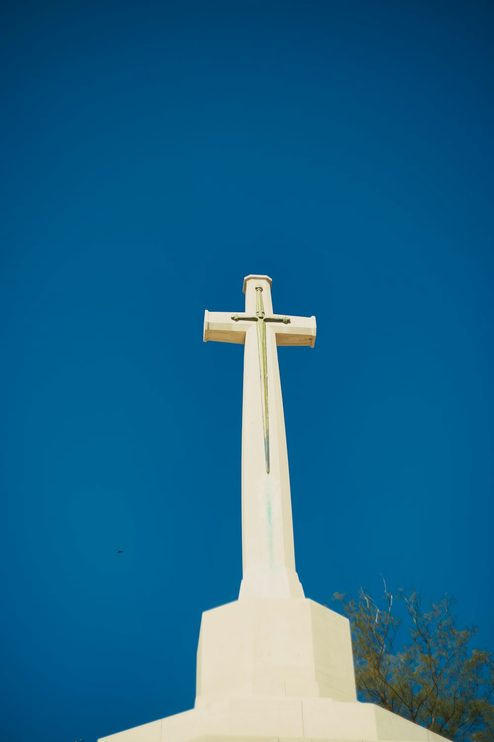 cruz blanca sobre hierba verde bajo el cielo azul durante el día