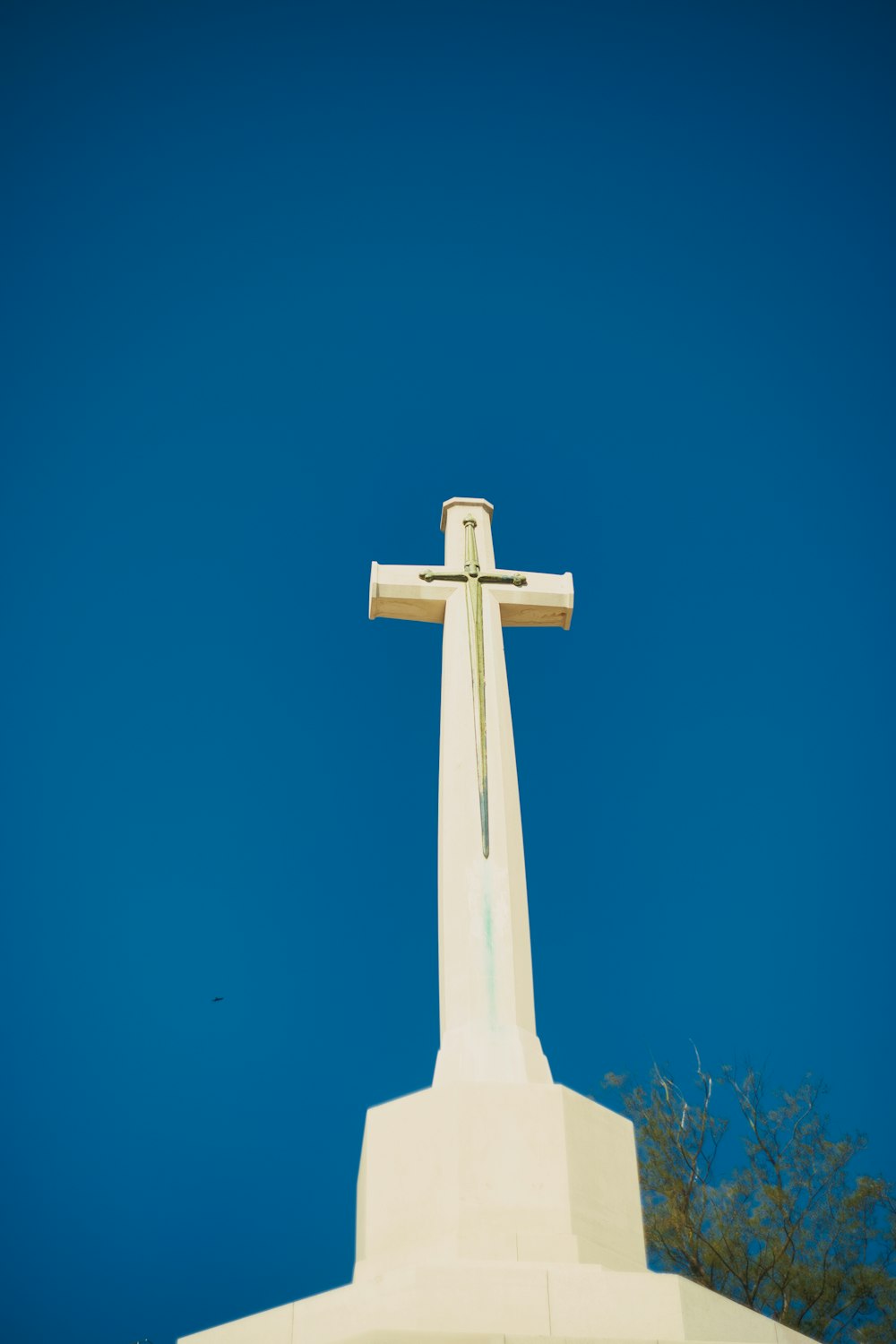 cruz branca na grama verde sob o céu azul durante o dia