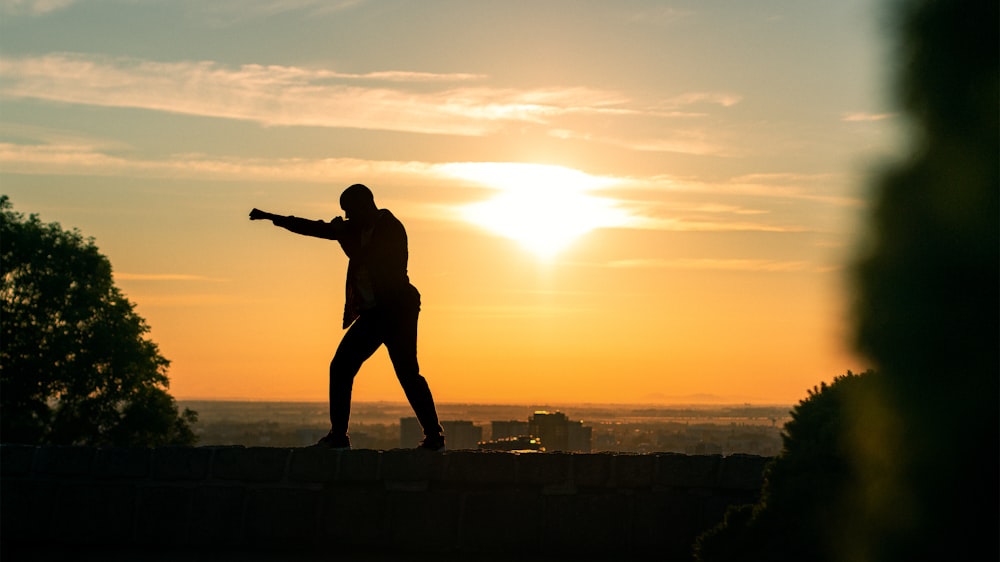 silhouette of man standing on rock during sunset