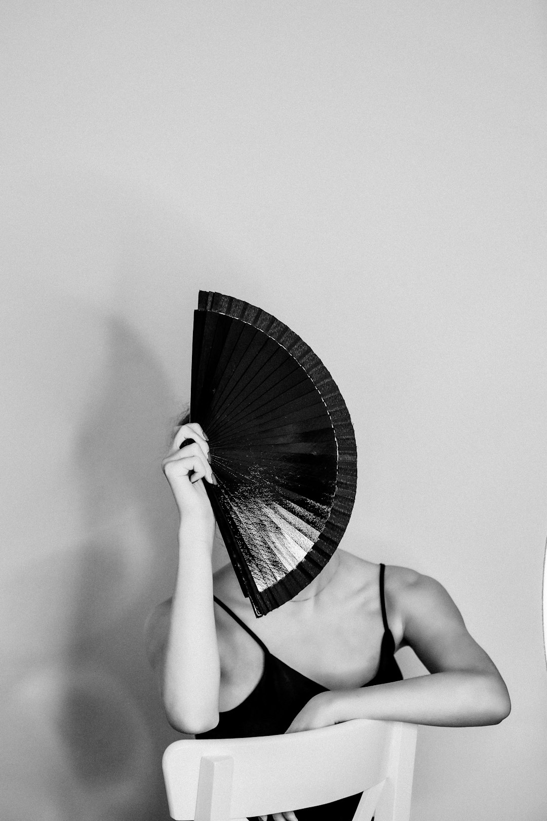 woman in black tank top covering face with hand fan