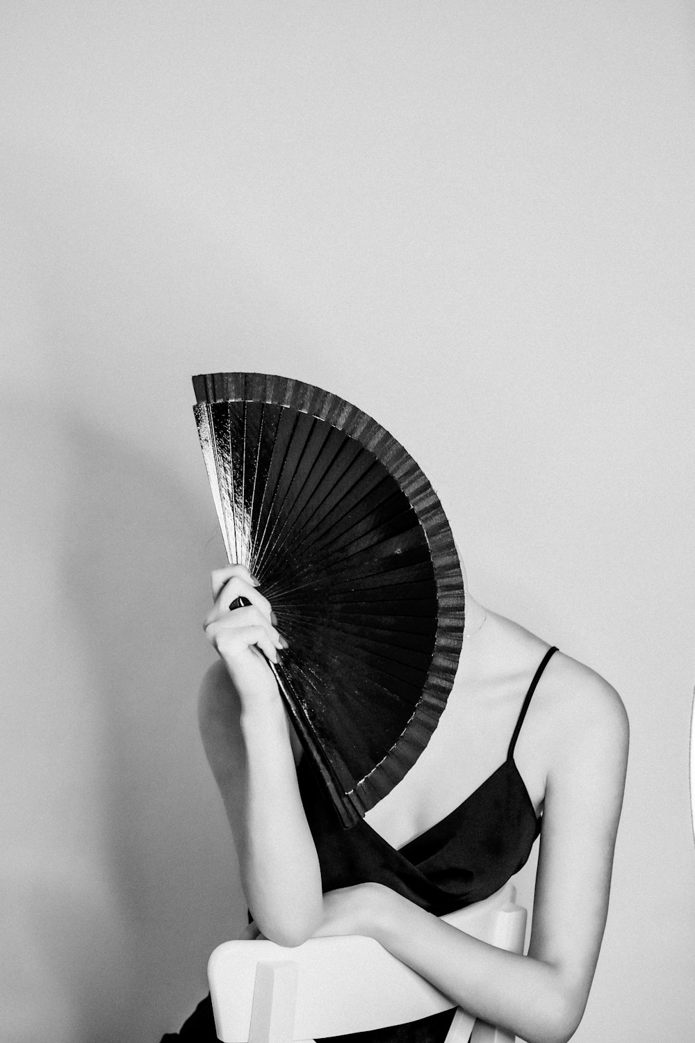grayscale photo of woman in black tank top holding hand fan