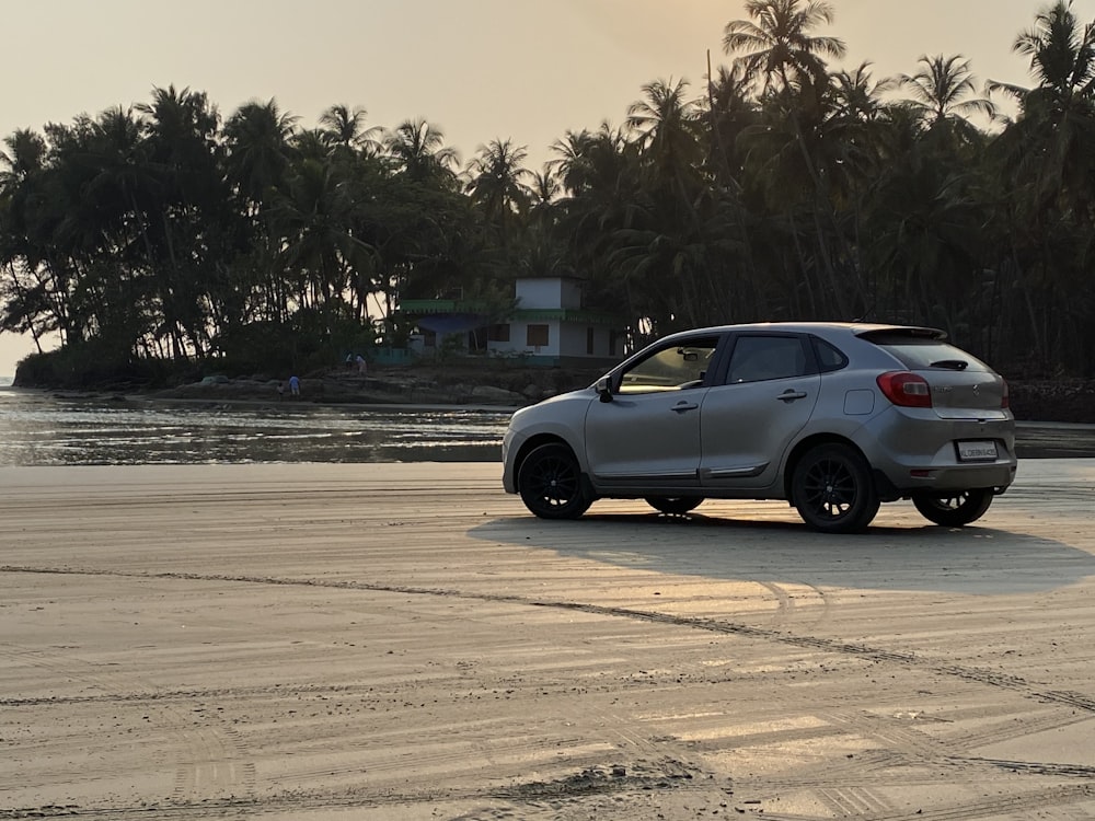 black sedan on gray sand near body of water during daytime