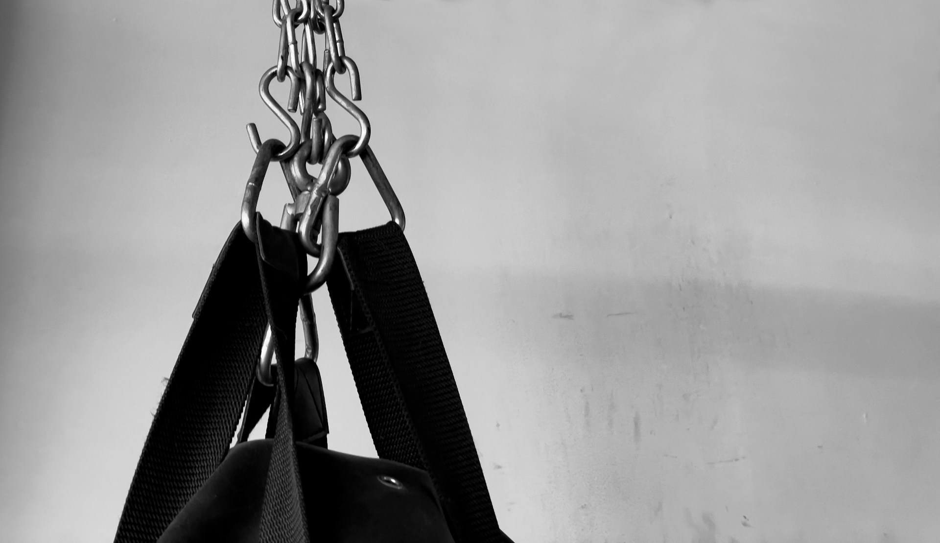 black leather sling bag hanged on white wall