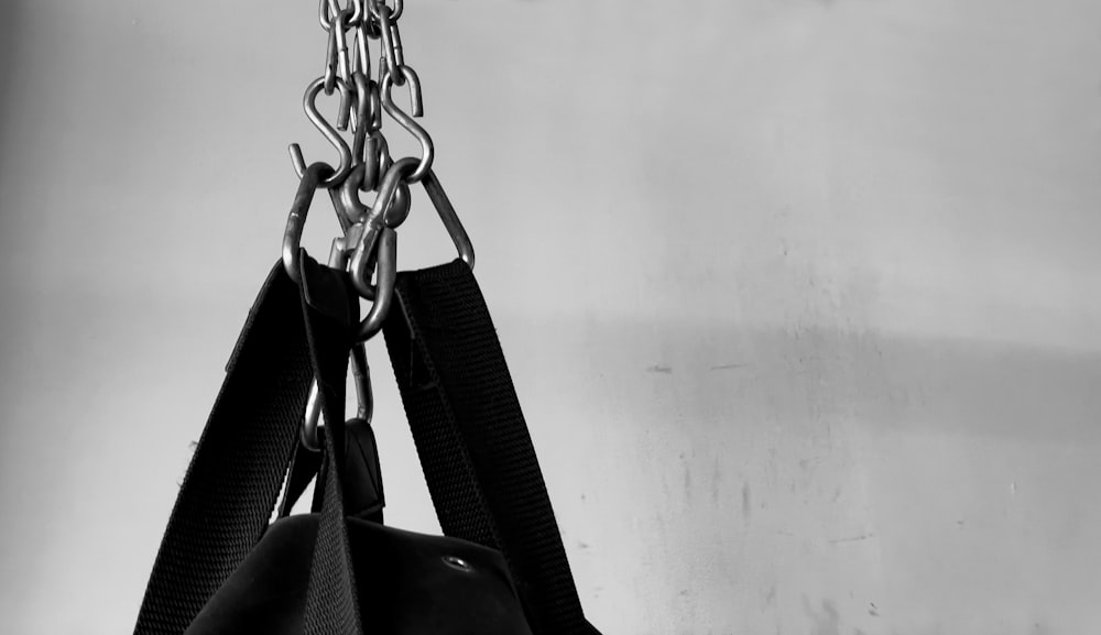 black leather sling bag hanged on white wall