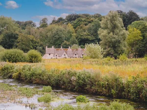 A stone house across a summer water meadow