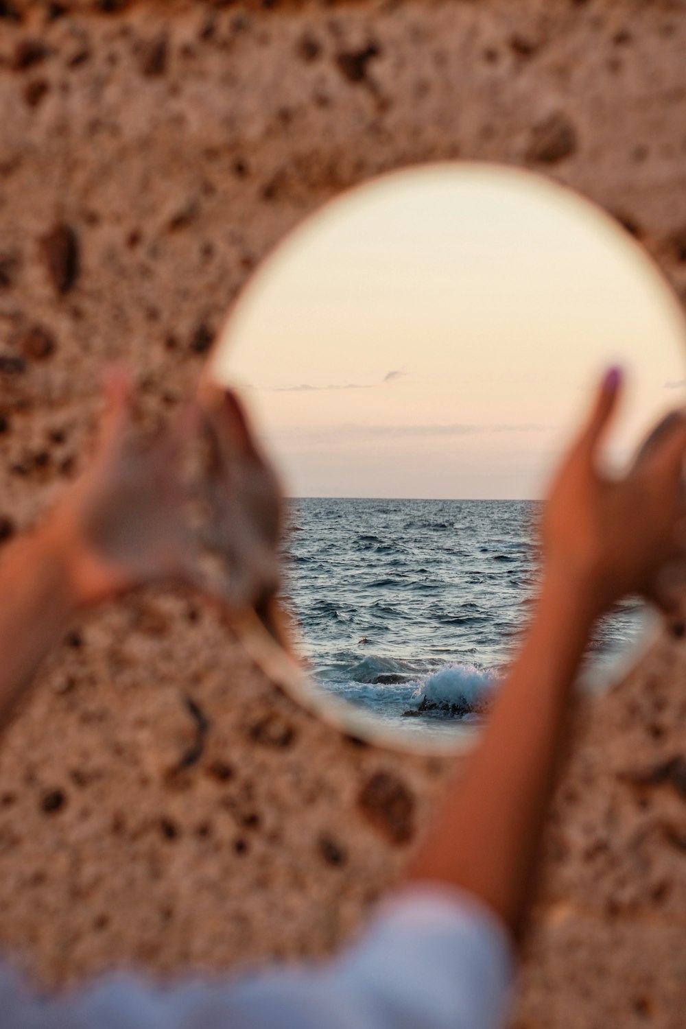 person holding white round ornament near body of water during daytime