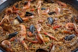 Close-up of a vibrant seafood paella cooking in a large pan outdoors