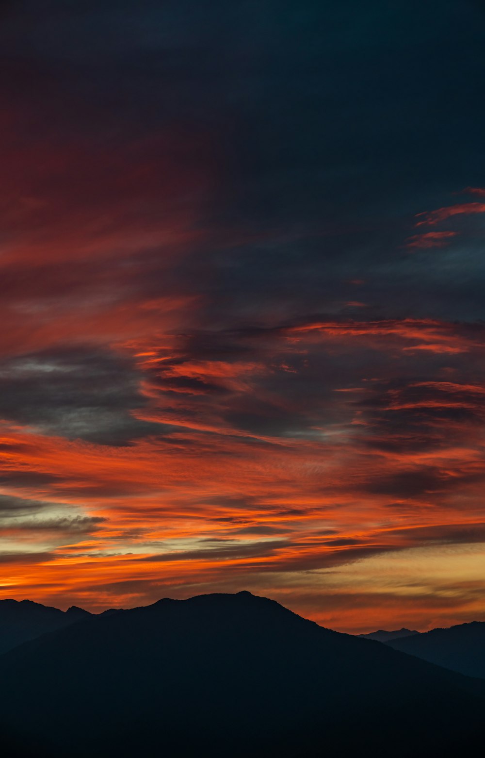 silhouette of mountains under cloudy sky during daytime