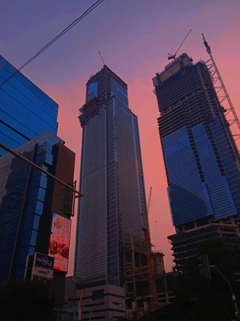 Photo showing workers installing a large billboard on a busy city street at sunset.