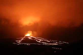 A breathtaking lava flow glowing orange under a dusky Hawaiian sky, surrounded by tropical foliage.
