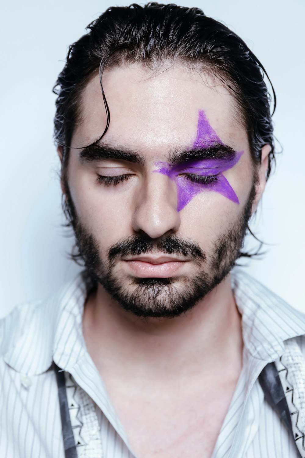 man in white and gray stripe shirt with purple and black eye shadow