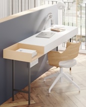 A sleek, minimalist workspace with dark gray walls and muted gold accents, featuring a modern desk and architectural sketches.