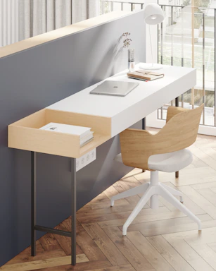 Modern minimalist interior workspace with architectural sketches and a laptop on a clean white desk.