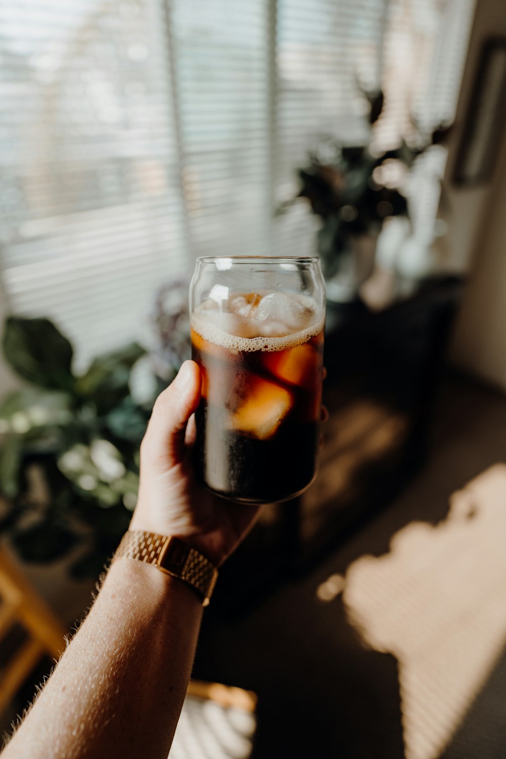 personne tenant un verre à boire transparent avec un liquide brun