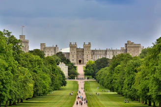 Foto do Castelo de Windsor, imponente construção medieval com torres e muralhas de pedra, cercada po