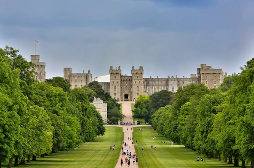 Foto do Castelo de Windsor, imponente construção medieval com torres e muralhas de pedra, cercada po