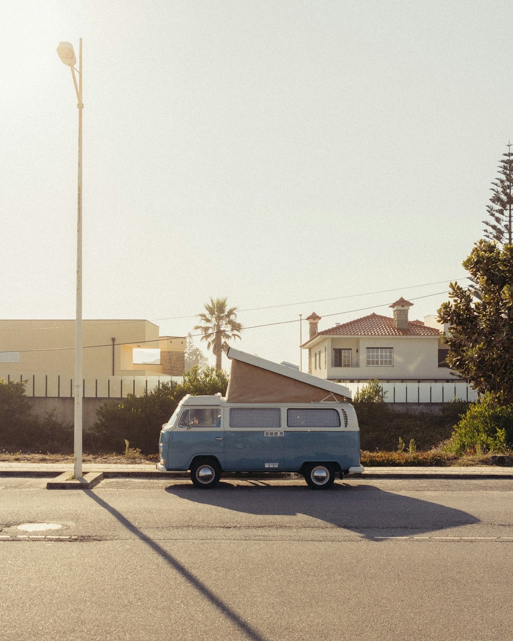 blue van parked on gray concrete road during daytime