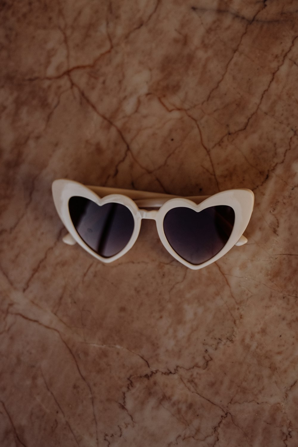 white framed sunglasses on brown surface