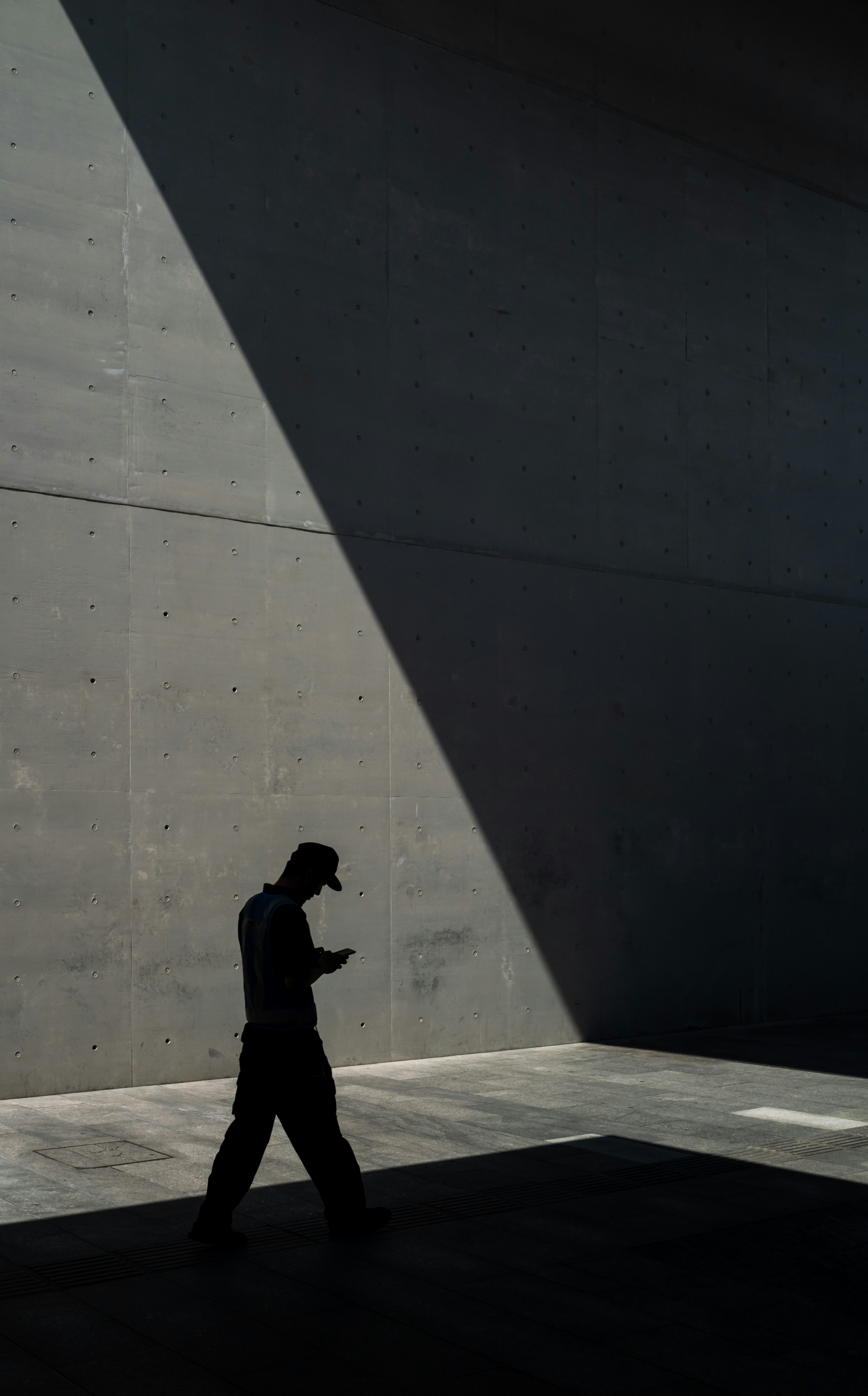 man in black jacket and pants standing near gray wall