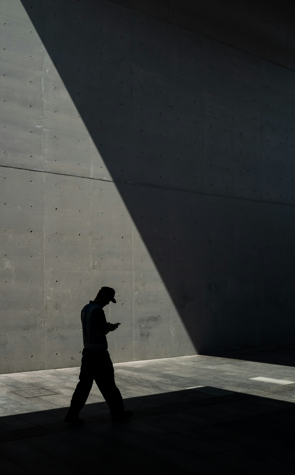 man in black jacket and pants standing near gray wall