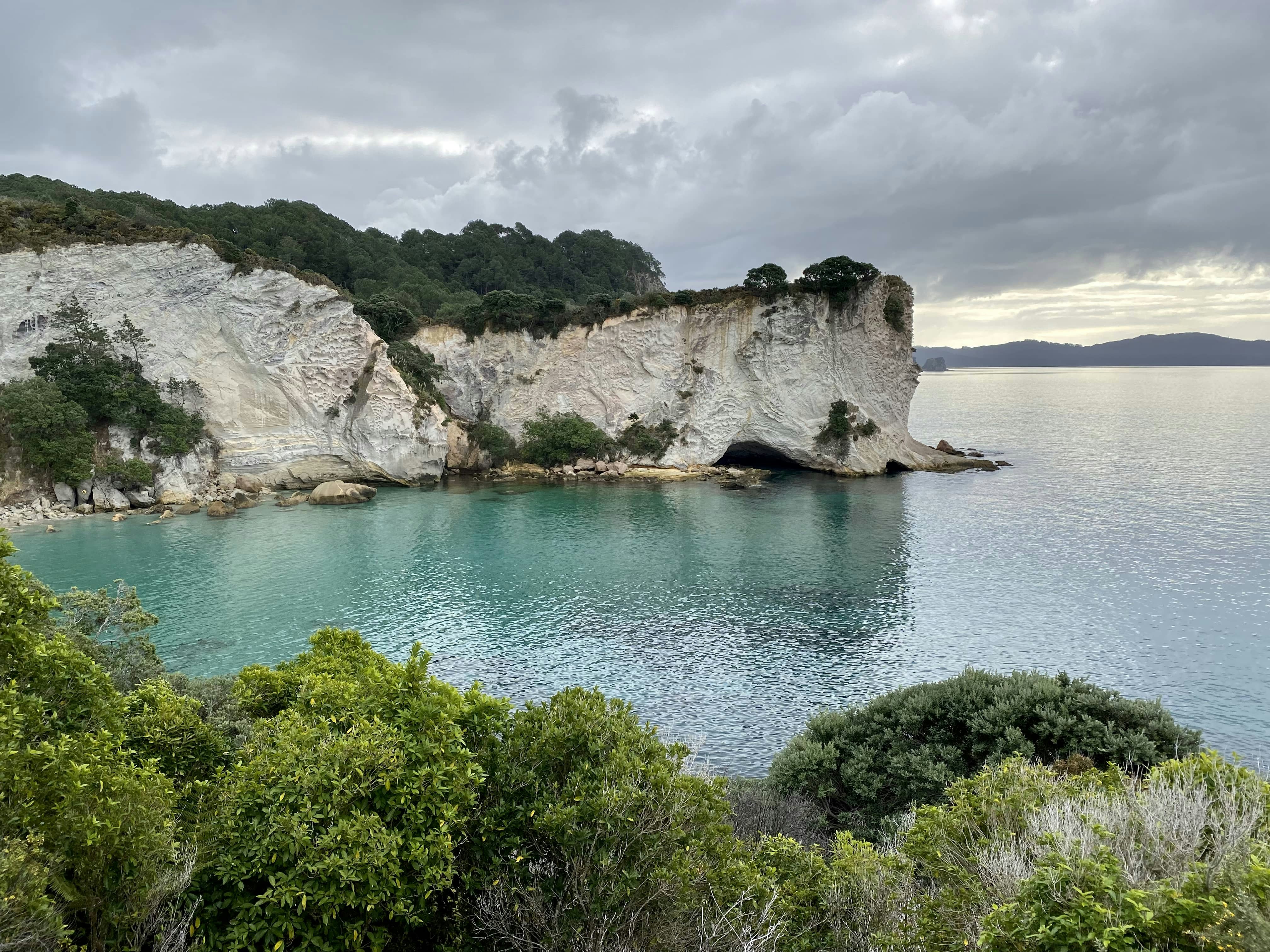 Grüne Bäume auf felsigen Bergen neben blauem Meer unter blauem Himmel und weißen Wolken tagsüber