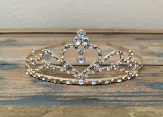 Close-up of a delicate crystal bridal tiara resting on a soft velvet cushion, glowing gently in natural light.